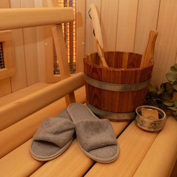 Grijze badstof sauna slippers op een houten saunabank