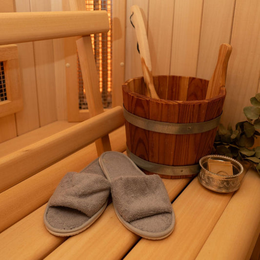 Grijze badstof sauna slippers op een houten saunabank