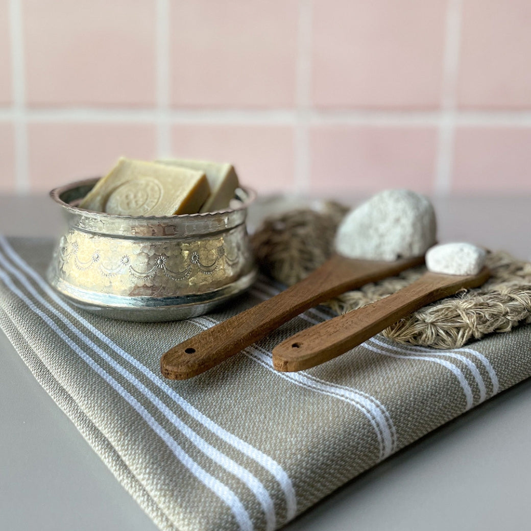 Hamamschaal met zeep en scrubwashandje in een sfeervolle badkamer.