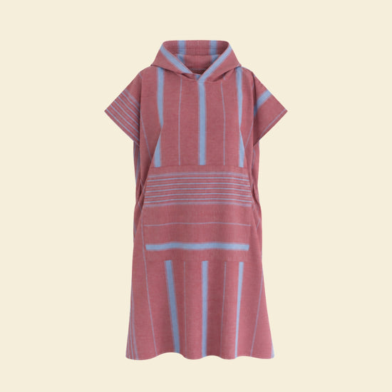 Bordeauxrode Ottomania Ege surfponcho met lichtblauwe strepen, capuchon en buidelzak op een crème achtergrond.