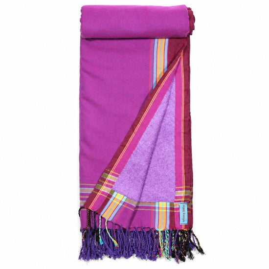 Opgevouwen PURE Kenya kikoy strandlaken Mandera Purple met paarse badstofvoering, gekleurde strepen en franjes.