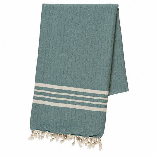 Groene hamamdoek in de kleur almond green met naturel strepen en franjes, netjes opgevouwen tegen een witte achtergrond.